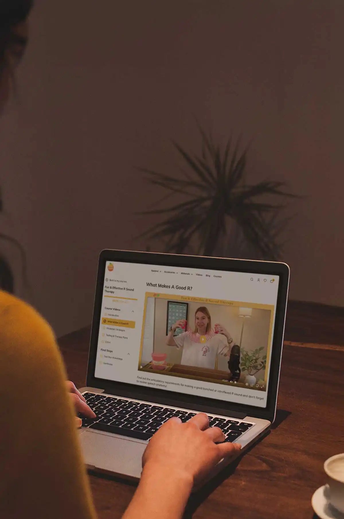 A person using a silver laptop with a video playing on the screen.