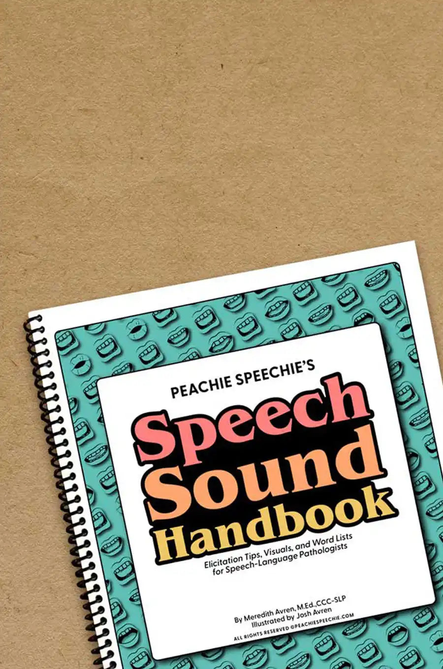 Spiral-bound ’Speech Sound Handbook’ with a teal patterned cover and coral-colored text.