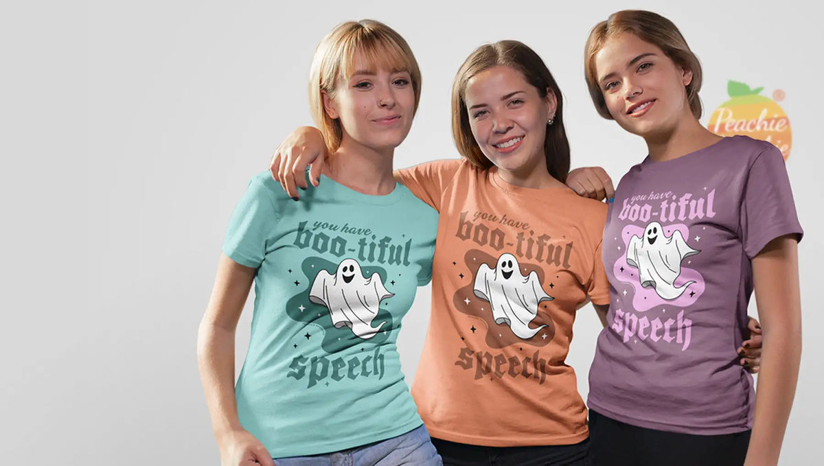 Three women wearing short-sleeved t-shirts with a ghost graphic and the text ’you have boo-tiful speech’ in varying colors.