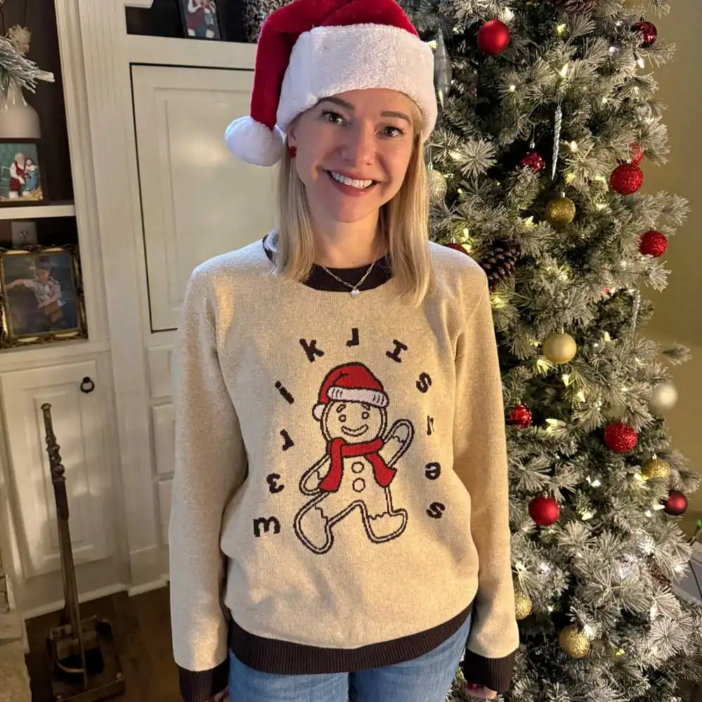 A cream-colored Christmas sweater featuring a dancing gingerbread character with musical notes.