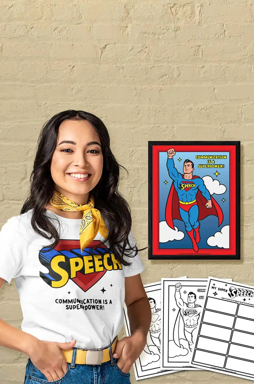 A smiling woman wearing a ’Speech’ Superman-themed T-shirt, next to a matching framed poster and coloring pages.